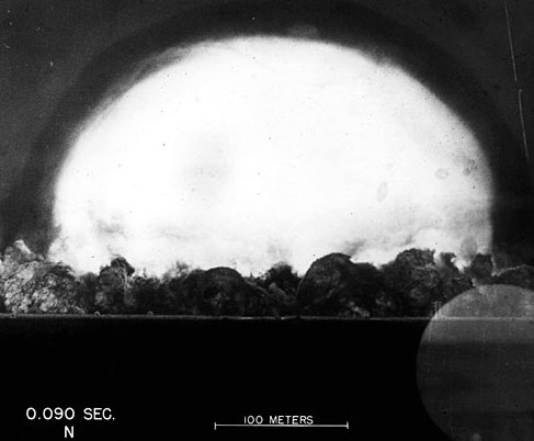 Black and white image of a giant mushroom cloud, bright against a dark background