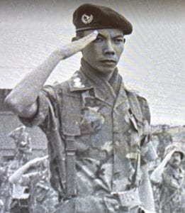 Chelsey Nguyen grandfather, shown in a black and white image from his time in the service, solemnly saluting in military uniform.