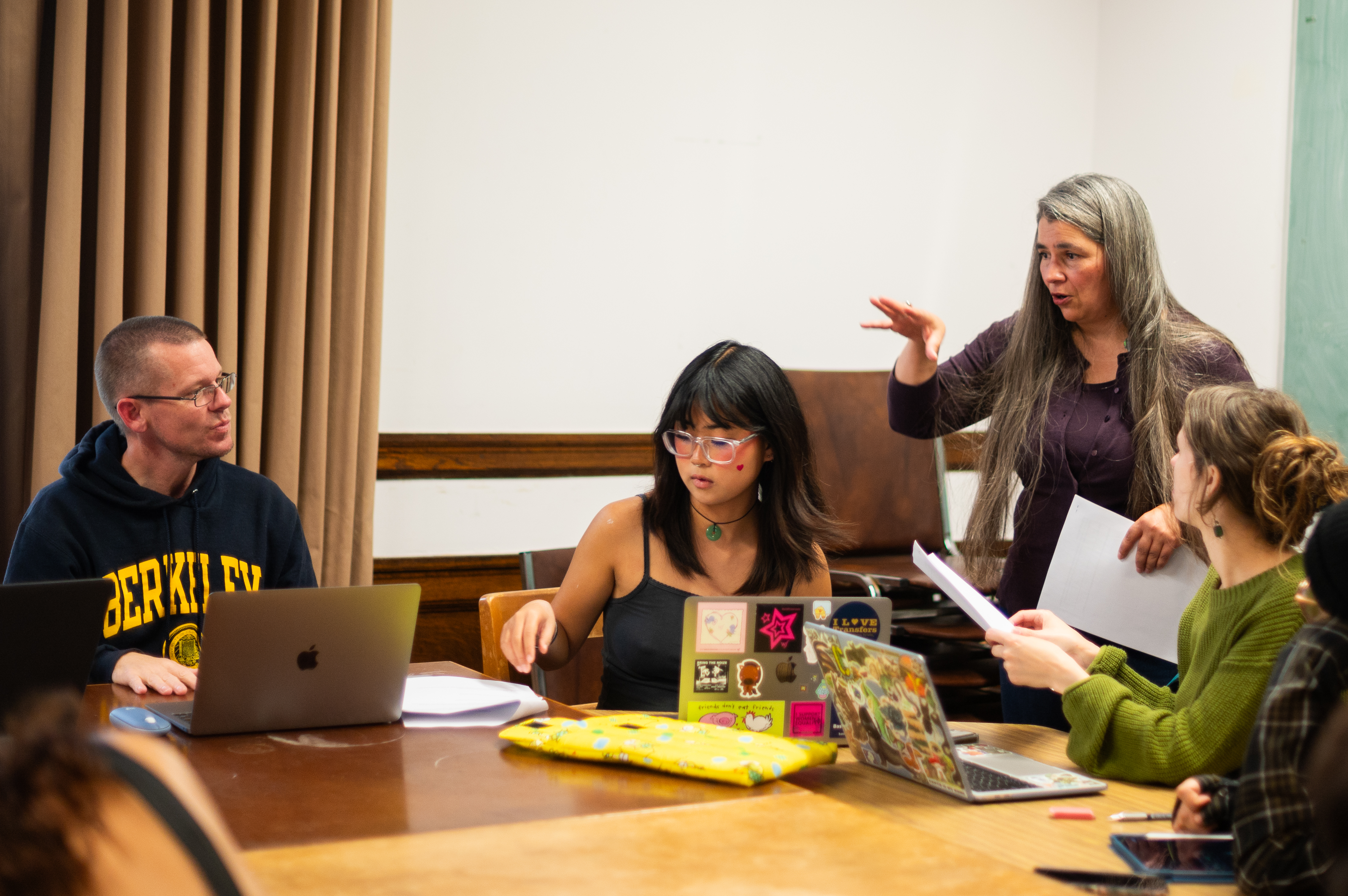 Carolyn Smith speaks to college-aged students sitting around a wooden table.