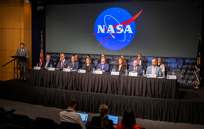 A panel of people at a NASA conference viewed from a distance