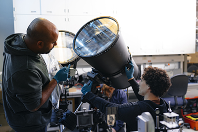 Two people putting together a telescope