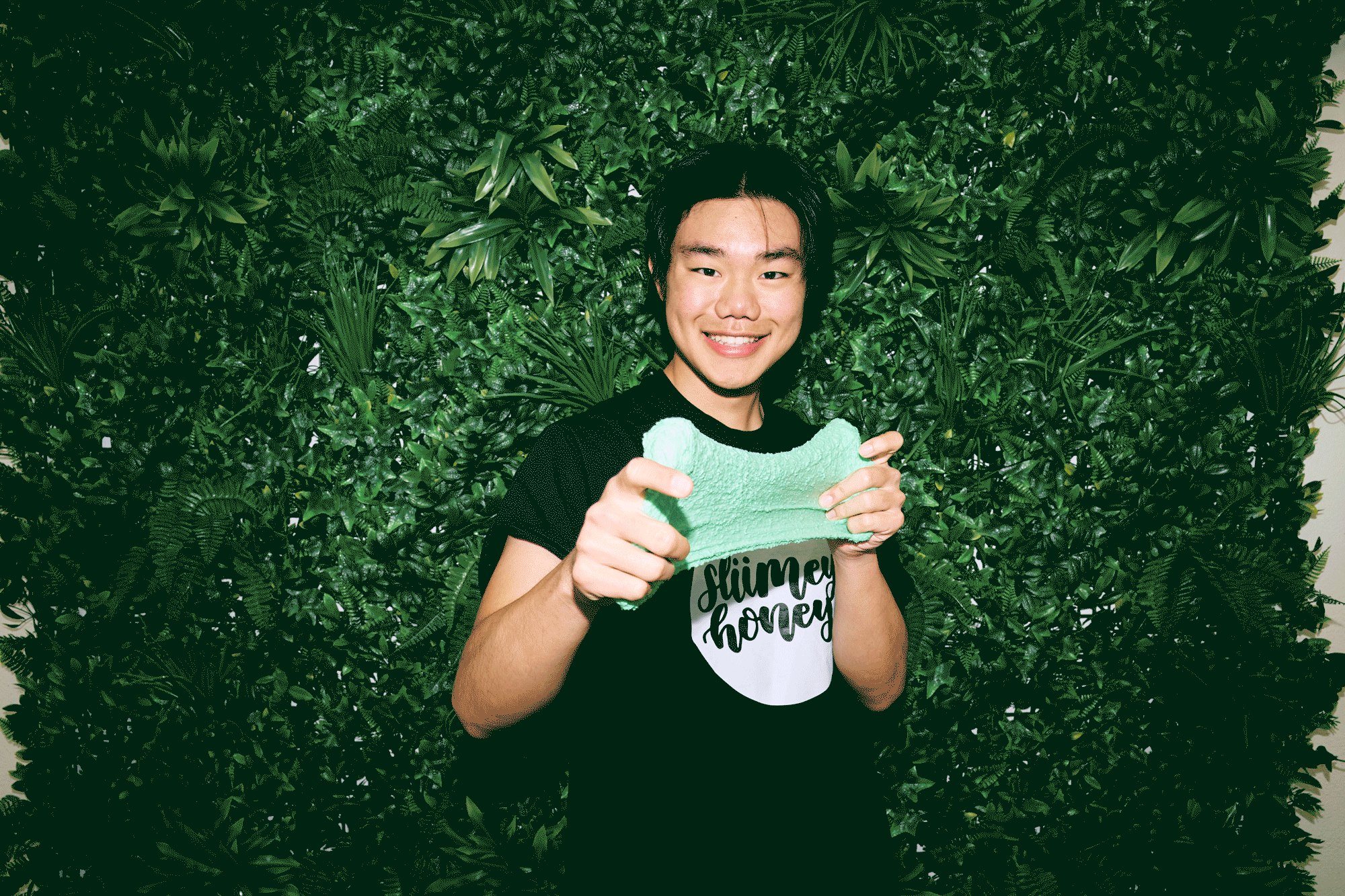 A young man of Asian descent, Mark Lin, plays with a slimy substance he invented, smiling