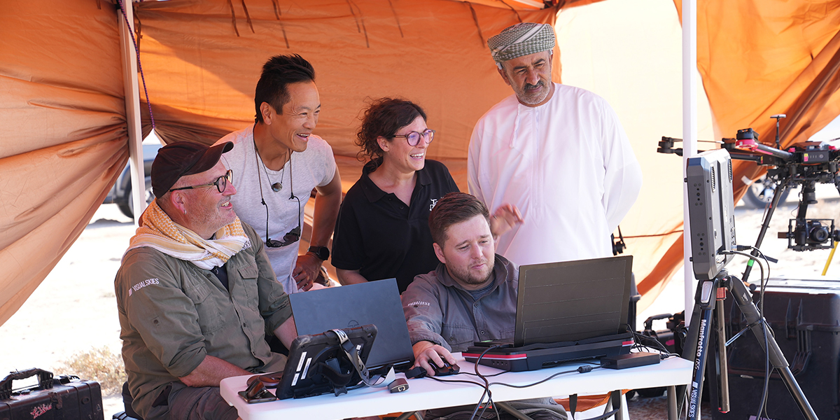 Albert Lin with a small group of people in a tent looking at a computer screen