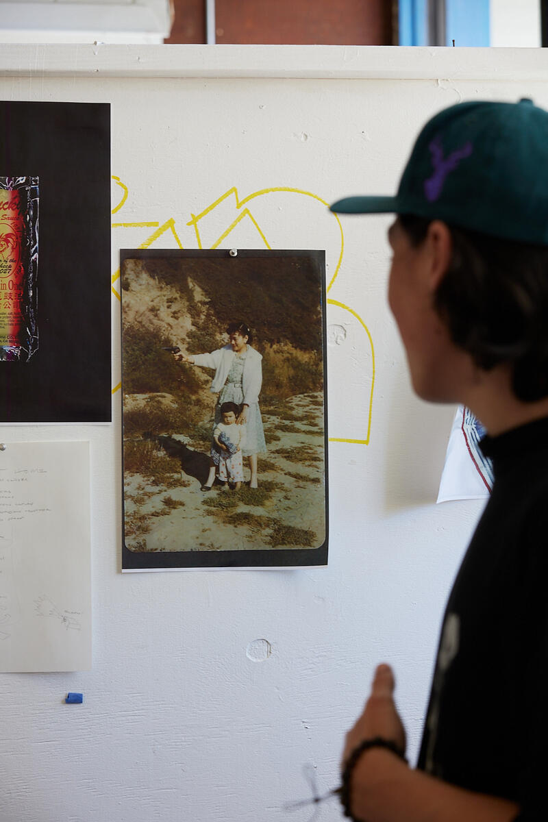an undergraduate student in a baseball cap looks at a photograph on a wall in an art studio