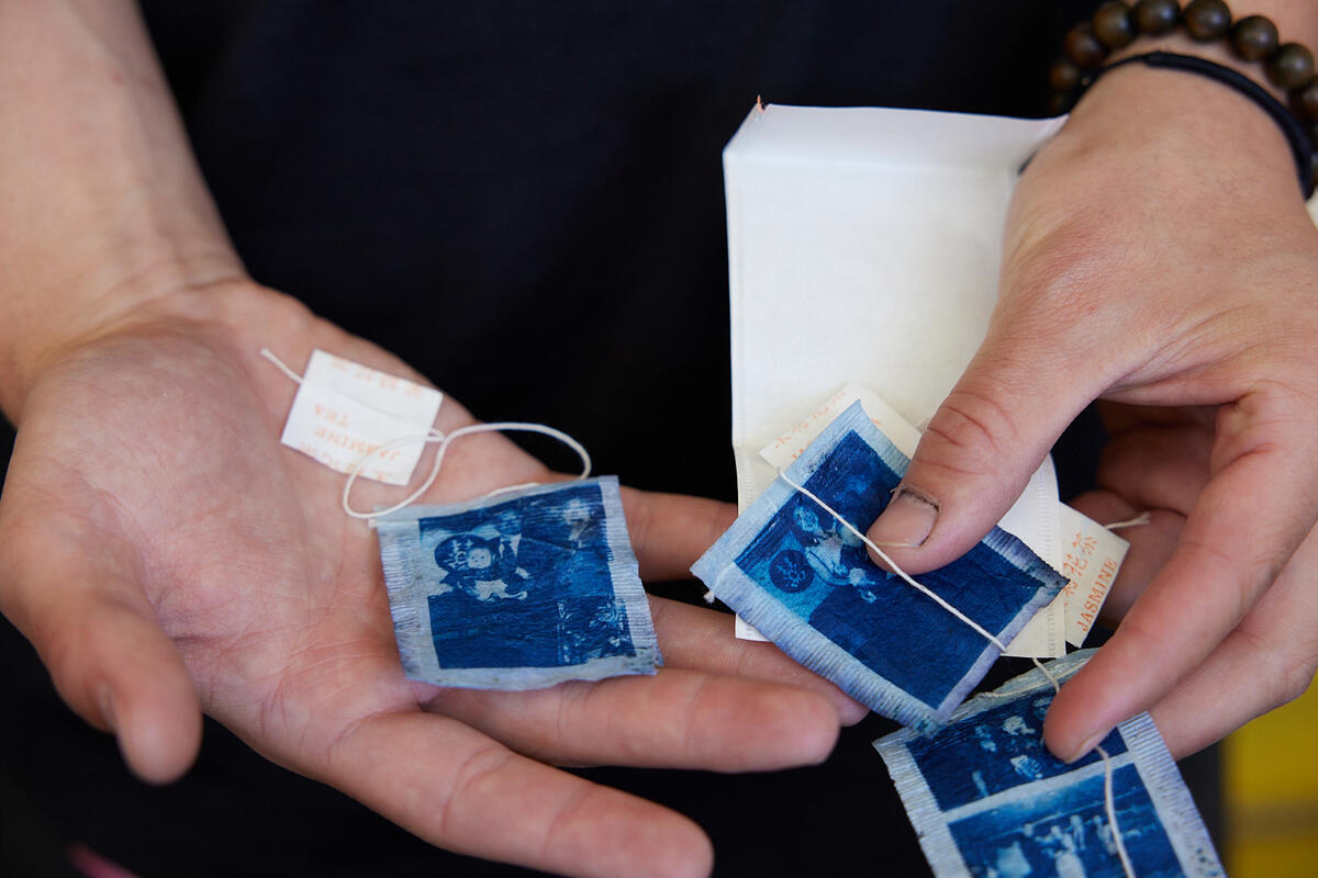 hands holding out an artwork of teabags printed with blue ink