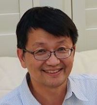 Headshot of George Liu, smiling, wearing glasses and a blue pinstripe collared shirt, with white shutters in the backdrop