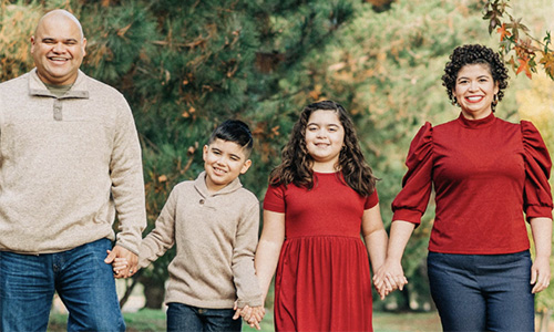 Two parents and two children smiling and holding hands