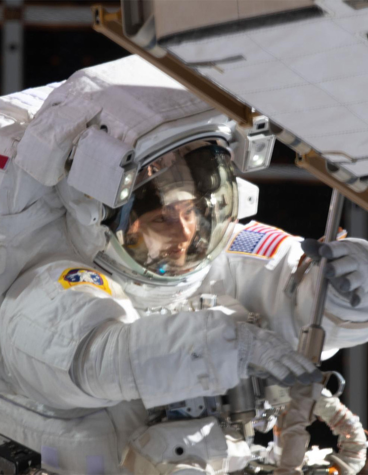Jessica Meir in a spacesuit using a tool during a spacewalk