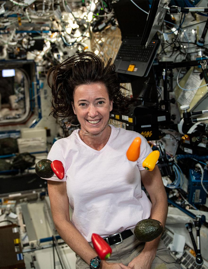Megan McArthur in zero gravity, with bell peppers and avocados floating in front of her