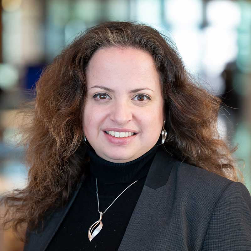 White woman smiling with brown curly/wavy hair