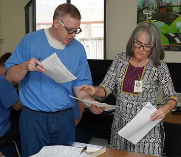 A prisoner and a teacher look at papers together