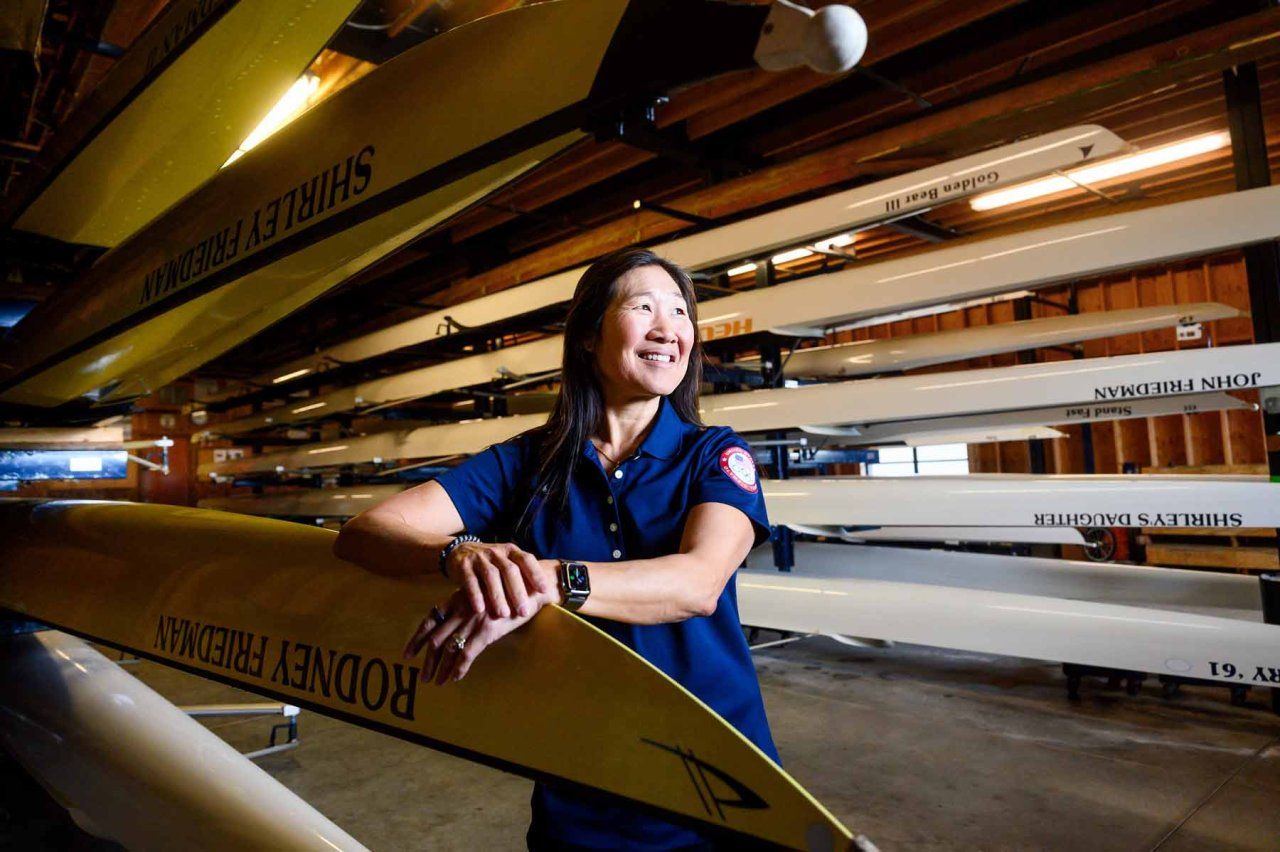 Cindy Chang smiles as she stands amid multiple rowing boats.