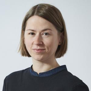 Celeste Kidd smiles for shoulders-up portrait against a light gray background