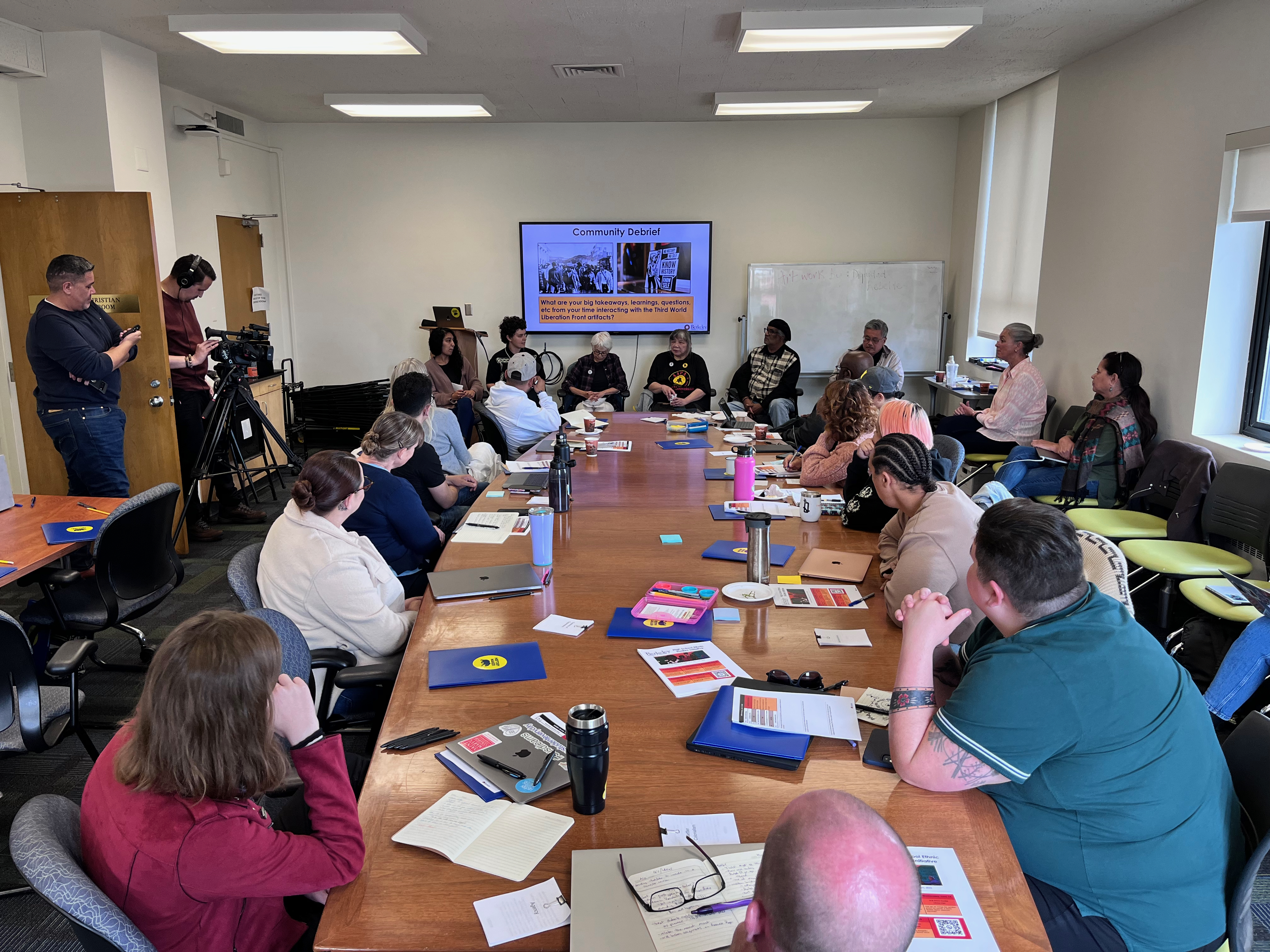 In a boardroom, California teachers listen to Third World Liberation Movement activists, at the front