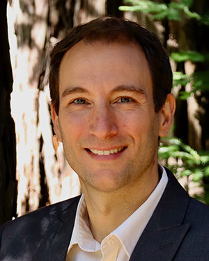 Ricardo Sanfelice, wearing collared shirt and suit jacket, smiles for a headshot, with a redwood tree in the background