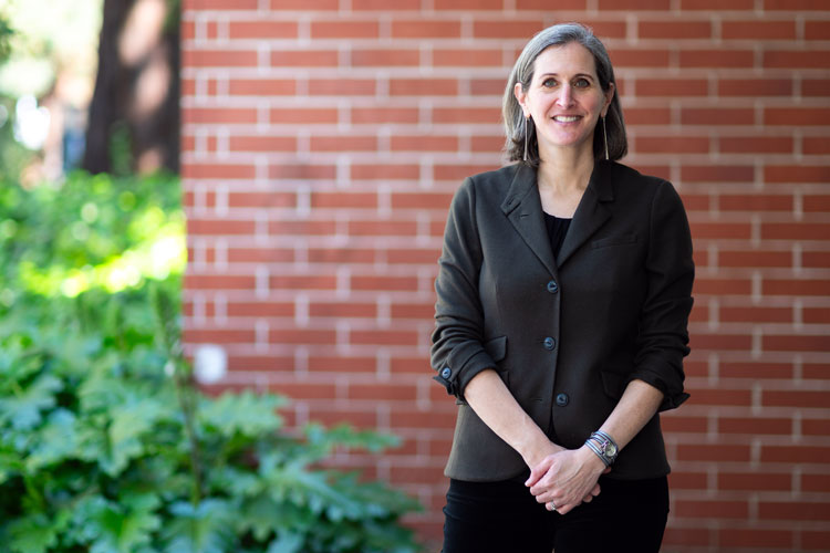 Amy Lerman smiles at camera standing in front of a brick wall