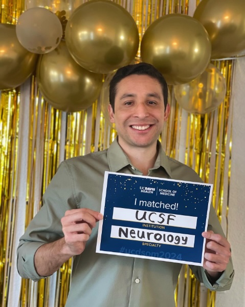 Javier Rodriguez holds a sign reading "I Matched! UCSF Neurology"