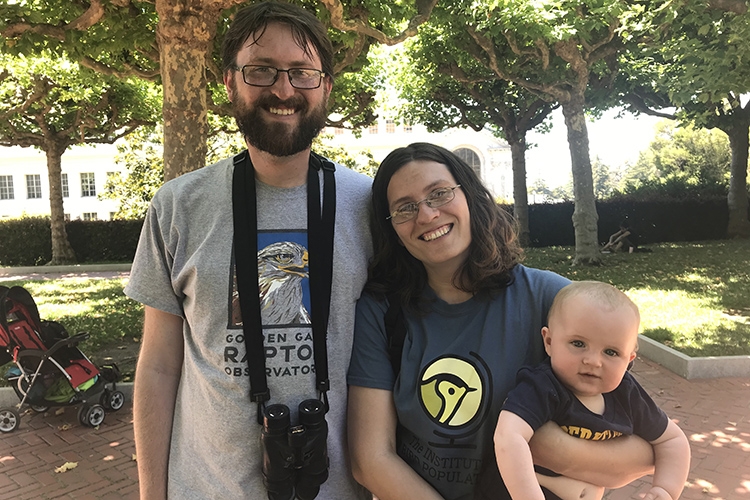 A man with a beard, a woman with shoulder-length hair holding a baby