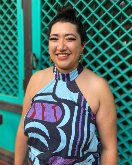 Sunaina Kale smiles for a portrait wearing a colorful, bold print dress