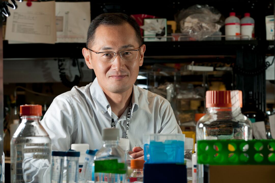 A man in glasses smiles in a lab