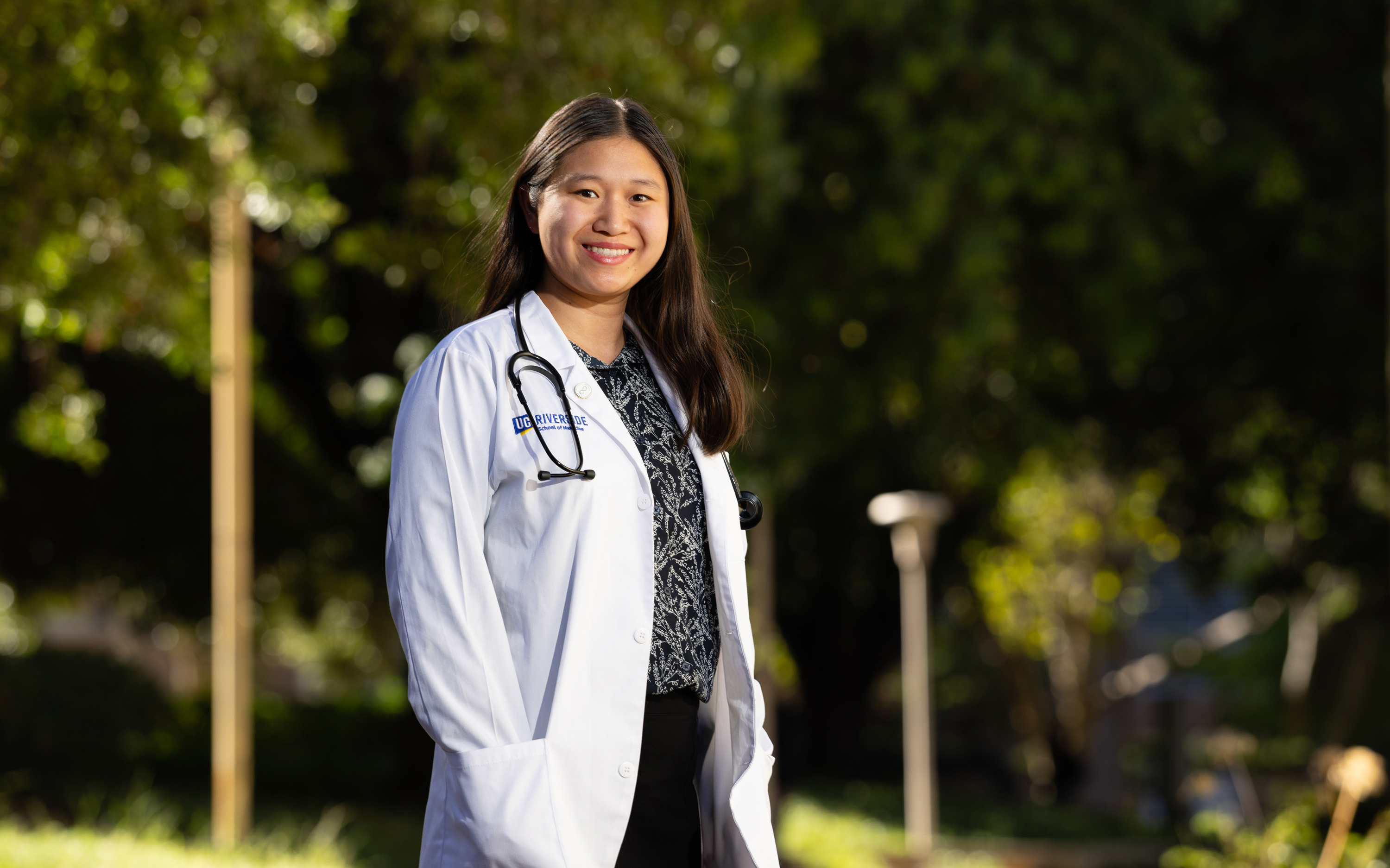 Portrait of Emily Li in a white UC Riverside lab coat with a stethoscope around her neck