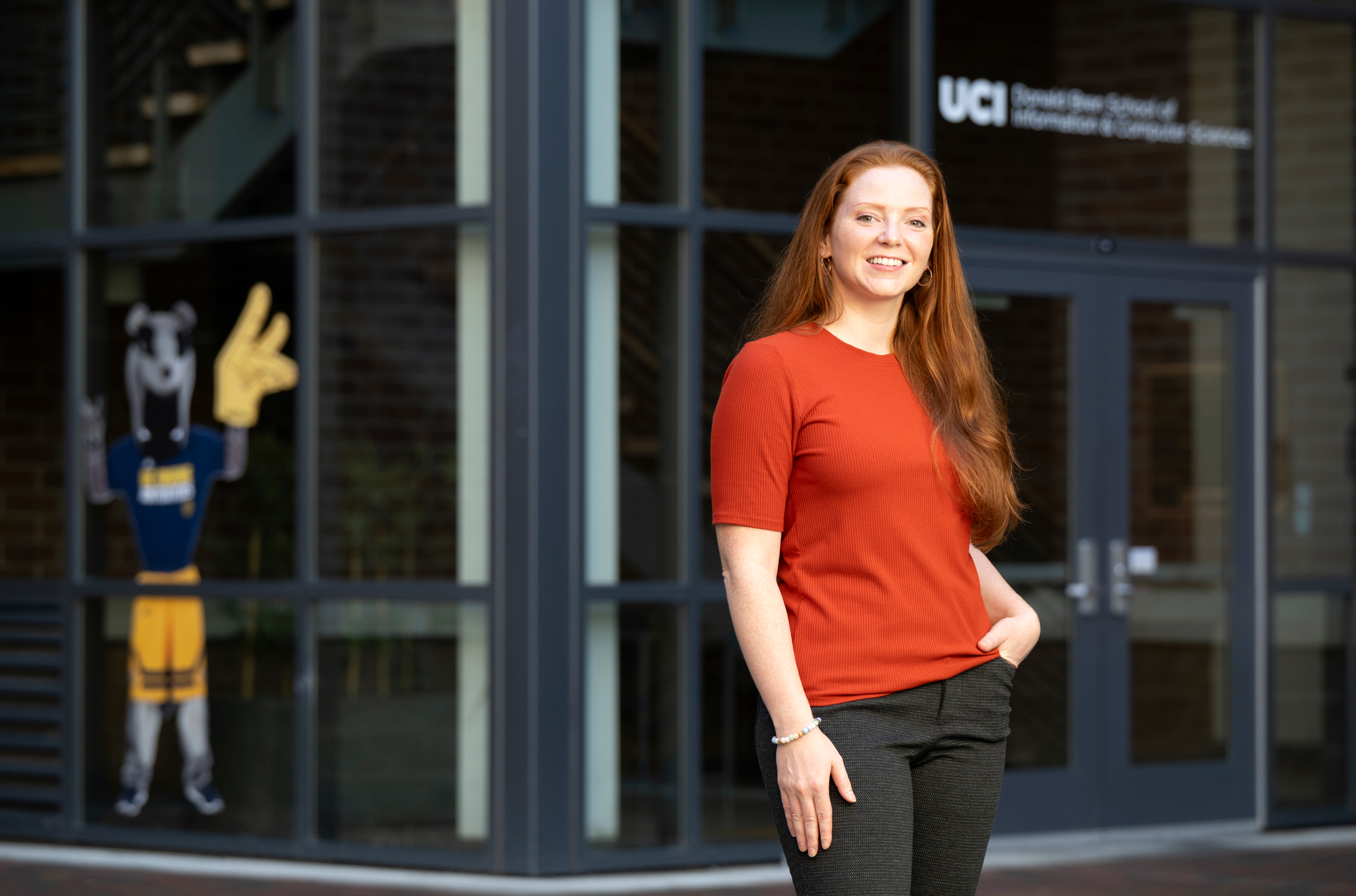 Portrait of Amanda Lassiter in front of a building at UC Irvine, with the Anteater mascot in the background