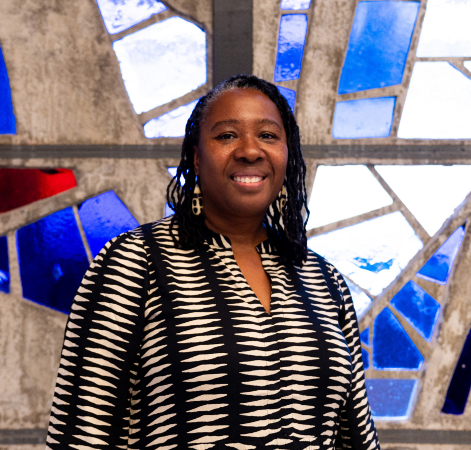 a woman smiles in front of a stained-glass window