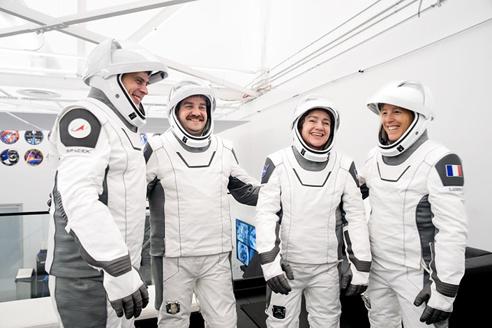 Four astronauts in white spacesuits suits together