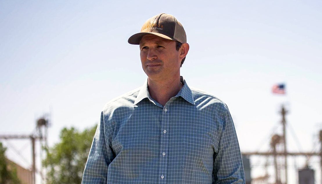 A man in a baseball cap and checked shirt on a farm
