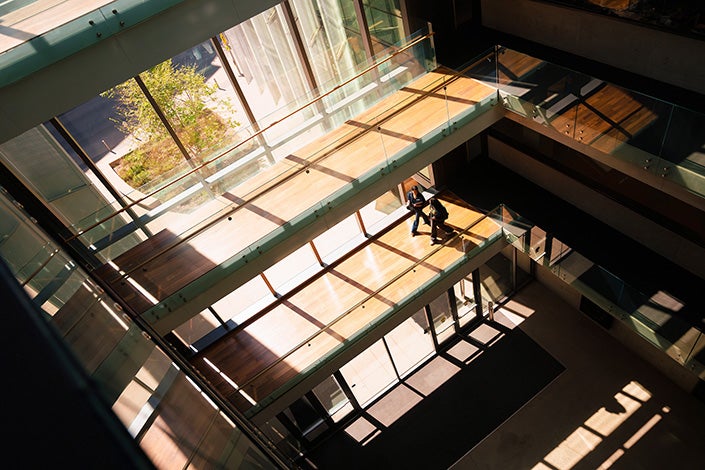 An overview view of two people walking through a brightly lit building with several exposed floors