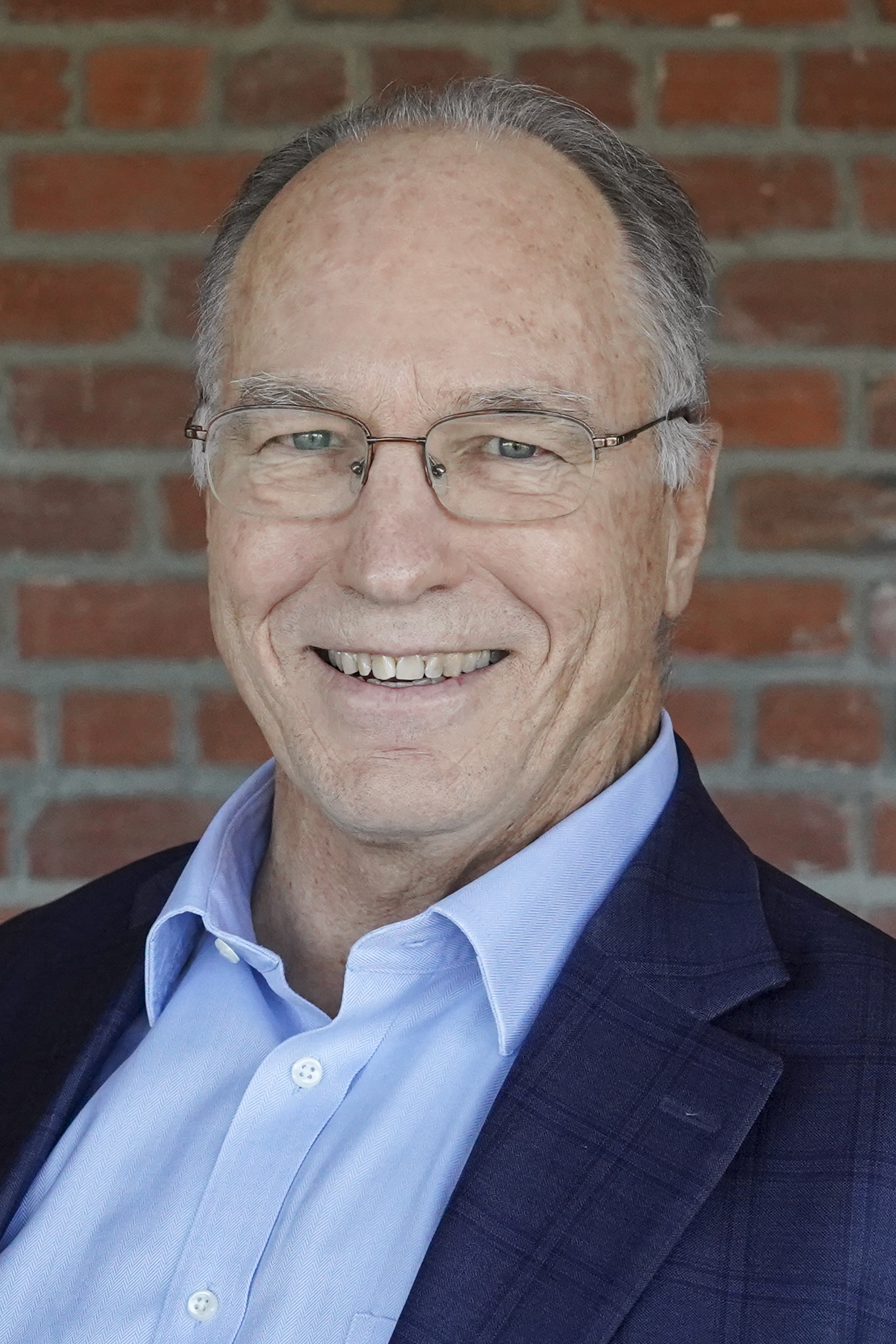A man in glasses with a blazer and dress shirt