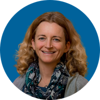 A woman with somewhat curly shoulder-length hair smiles in a headshot