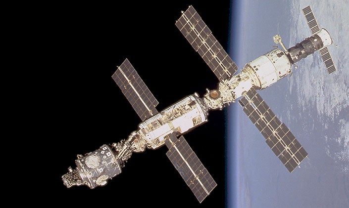 The International Space Station, with its two wide sets of solar panels, floats in orbit around the Earth