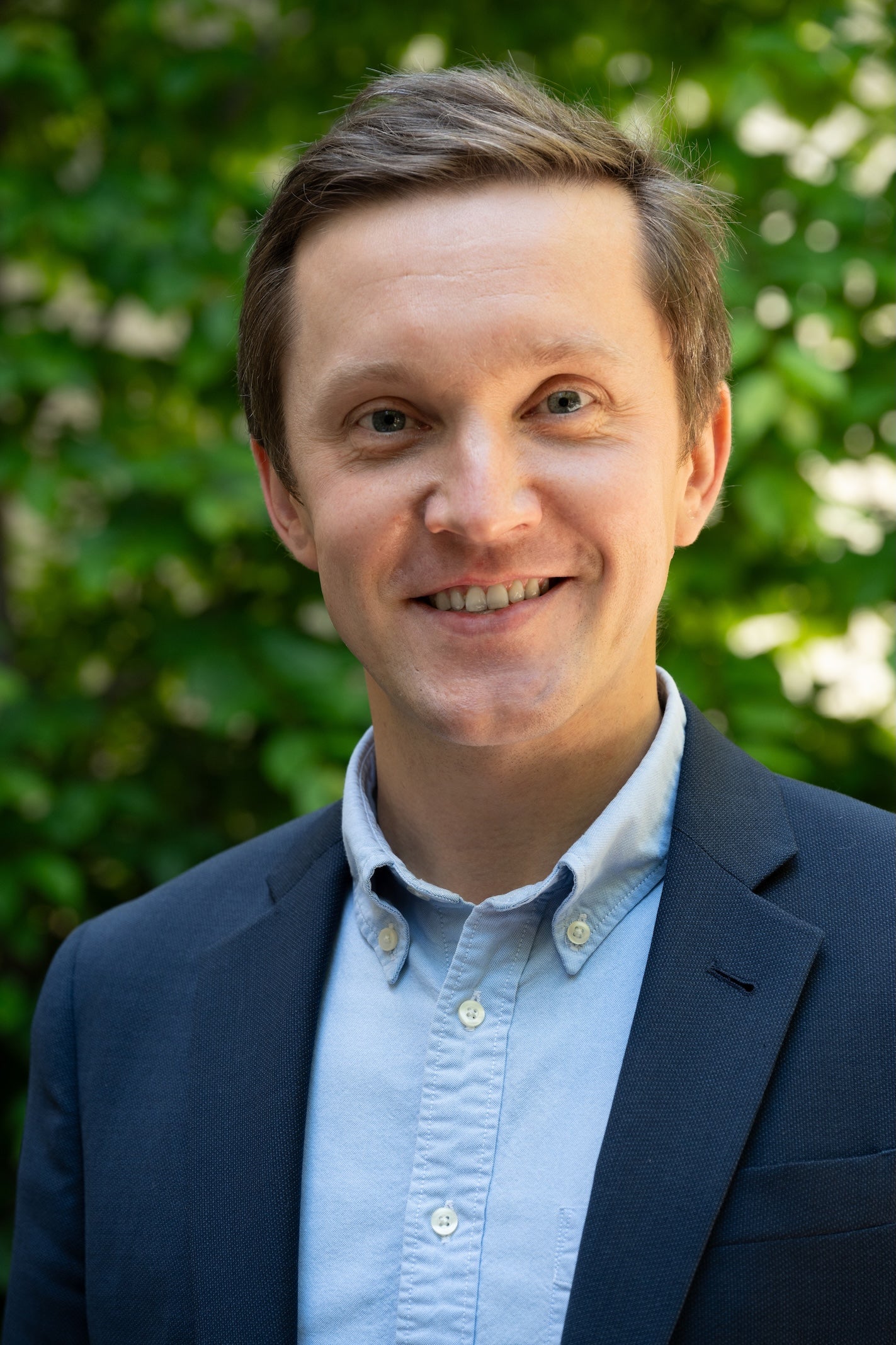 A man in a light blue dress shirt and dark blue blazer