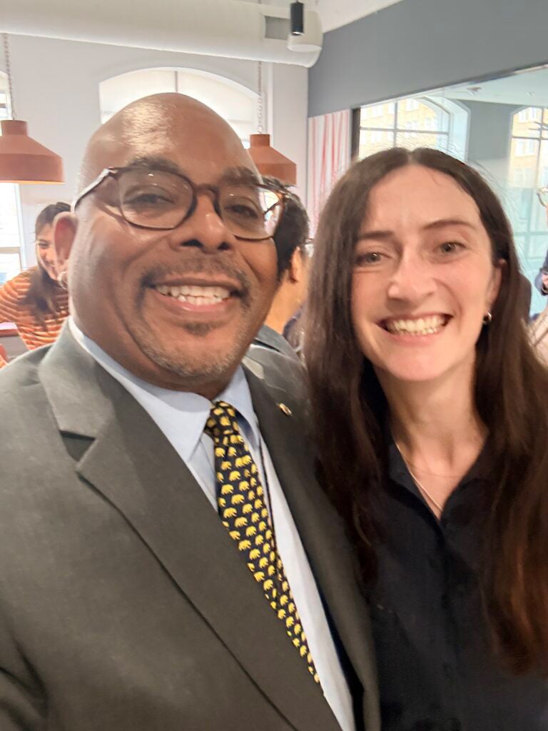 a man in a suit smiling next to a woman with shoulder-length hair in a selfie