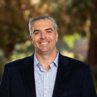A man with a suit jacket smiles