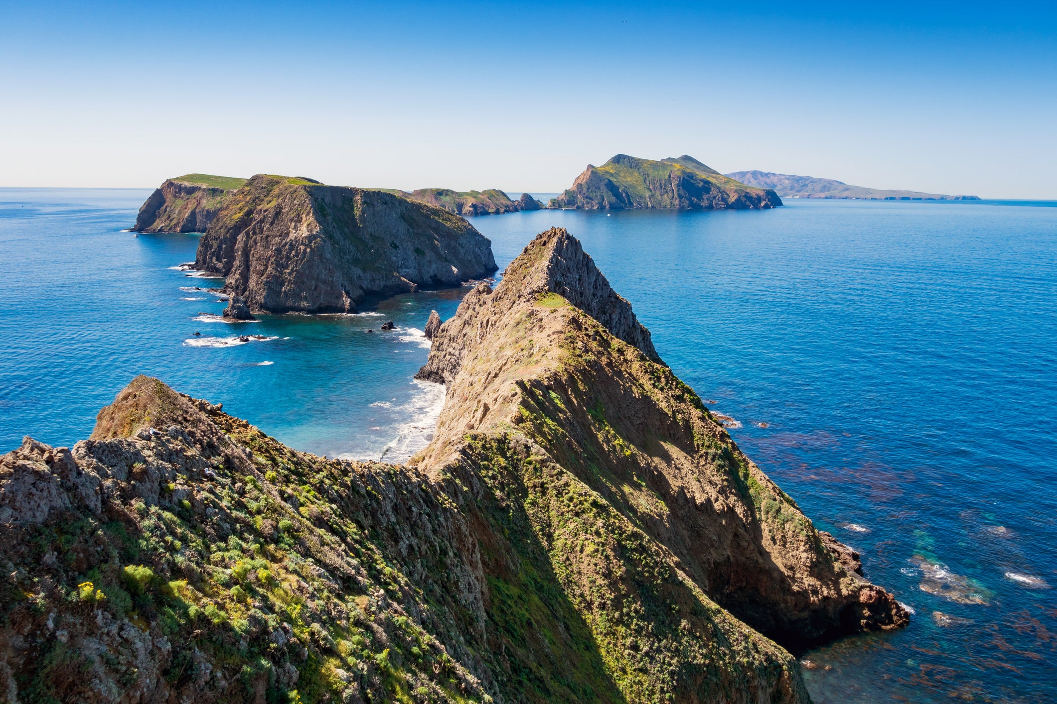 Rocky, grass-topped islands rise from the bright blue Pacific Ocean at Channel Islands National Park.