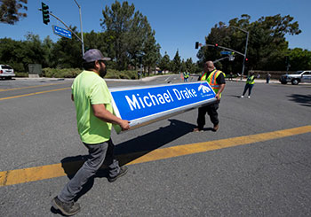 Workers carry the Michael Drake street sign