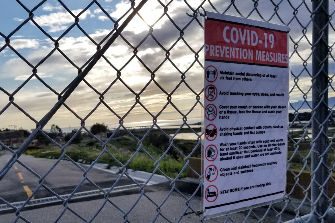 Sign on a fence about COVID-19 prevention measures Sign on a fence about COVID-19 prevention measures