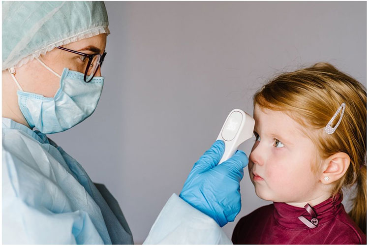 Child being tested for a fever by a healthcare worker