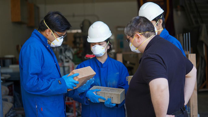 Group of four researchers examining earth blocks