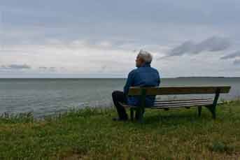 Man sitting on a bench looking out over water