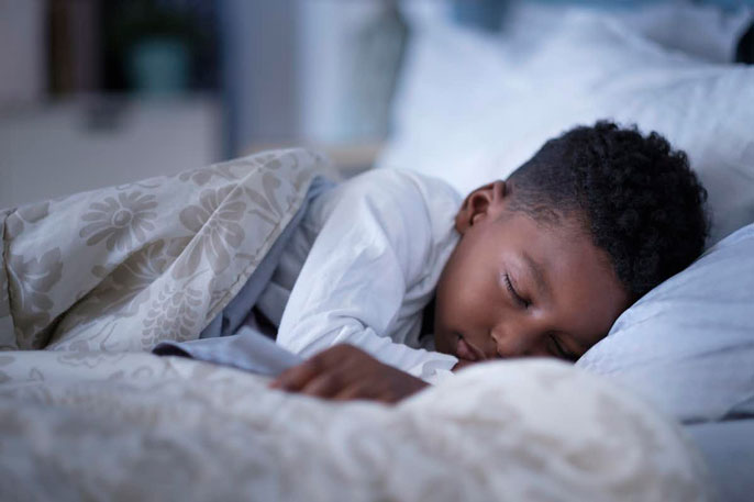 A young boy sleeping under the covers