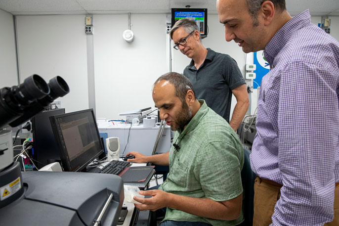 Scientists study bone samples near a computer