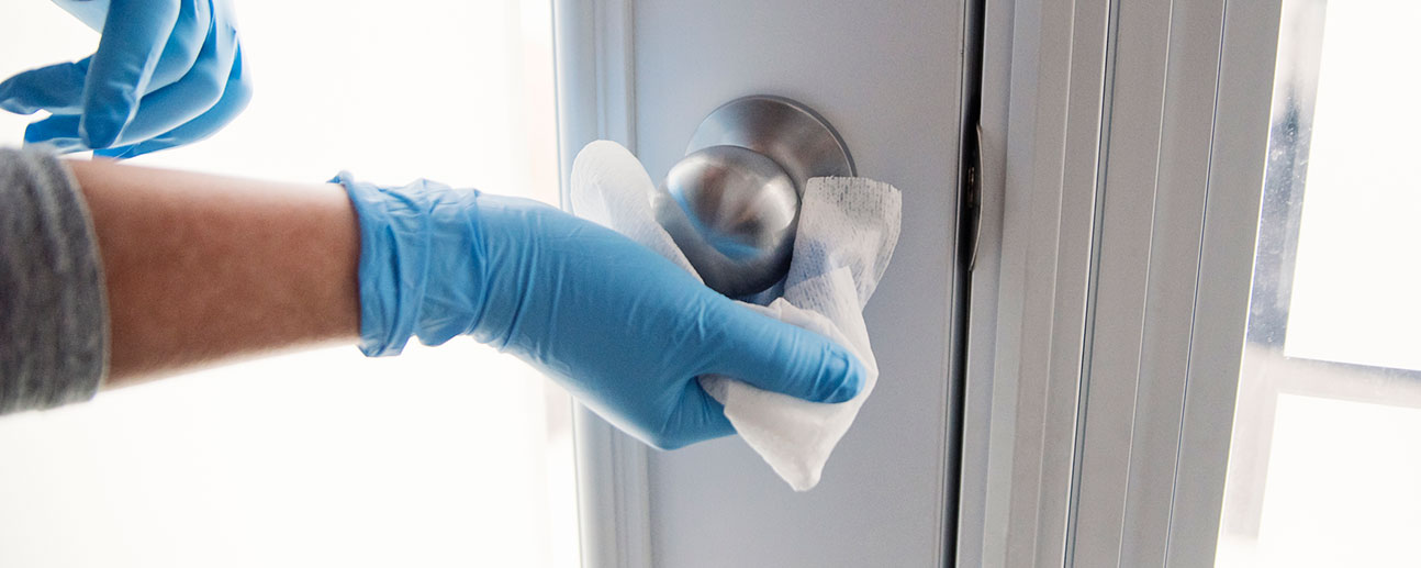 someone wearing gloves cleaning a door knob