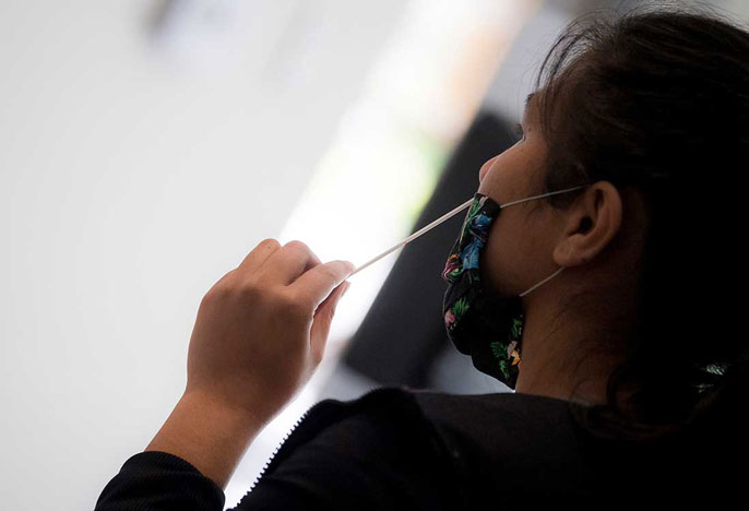 Woman in mask administers a test