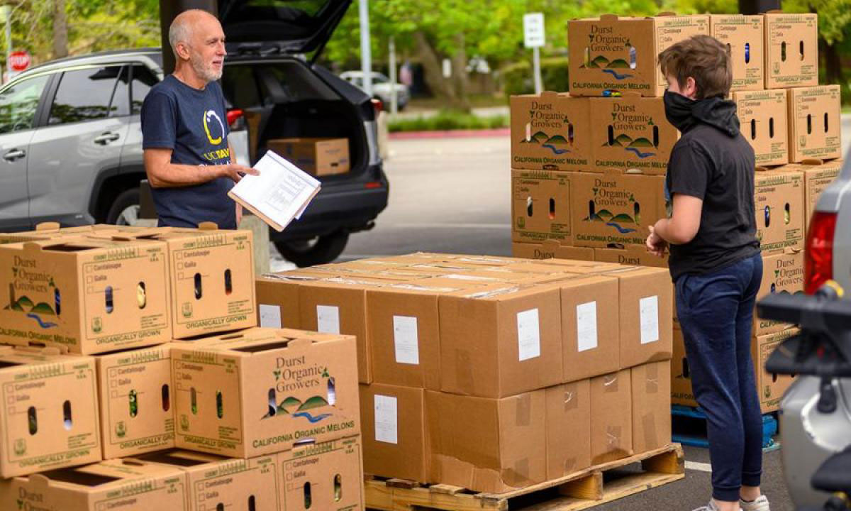 Man and teen next to lots of produce boxes