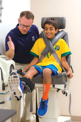 Kid stretching leg with researcher standing by