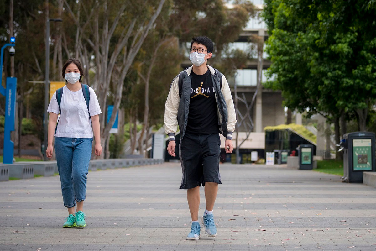 Two students walking with facemasks on