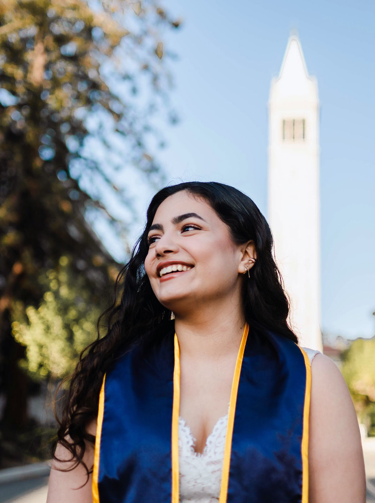 Frida in graduation clothes in front of Sather Tower UC Berkeley